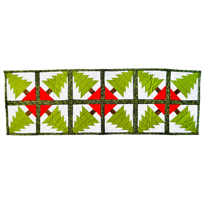 A rectangular quilted table runner featuring a repeating pattern of green Christmas trees on white panels, separated by red X-shaped centers and dark green borders.