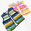Two sleeveless patchwork vests laid flat on a white background. The front vest is navy blue with horizontal stripes of yellow, green, and orange, featuring a shark pattern.