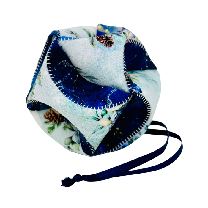 A fabric drawstring pouch with a light blue and navy blue winter forest print, featuring pinecones and white flowers, with a navy blue drawstring cord.