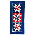 A vintage-style quilt runner featuring three vertical panels with red, white, and blue starburst patterns, finished with a wide blue border.