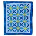 A square quilt with a geometric starburst pattern, featuring shades of blue, navy, and yellow on a white background with a blue border.